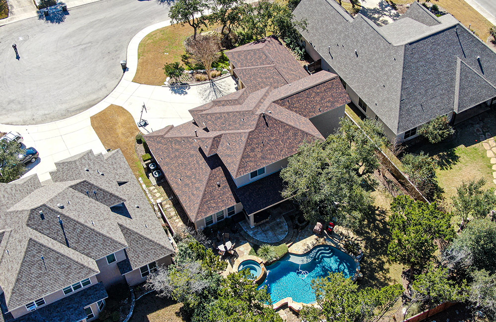 an aerial view of three different roofs with grey and brown shingle systems