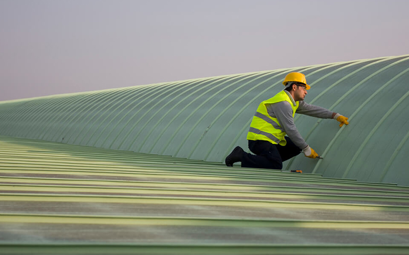 a professional construction worker applying the finishing touches to a metal roof system