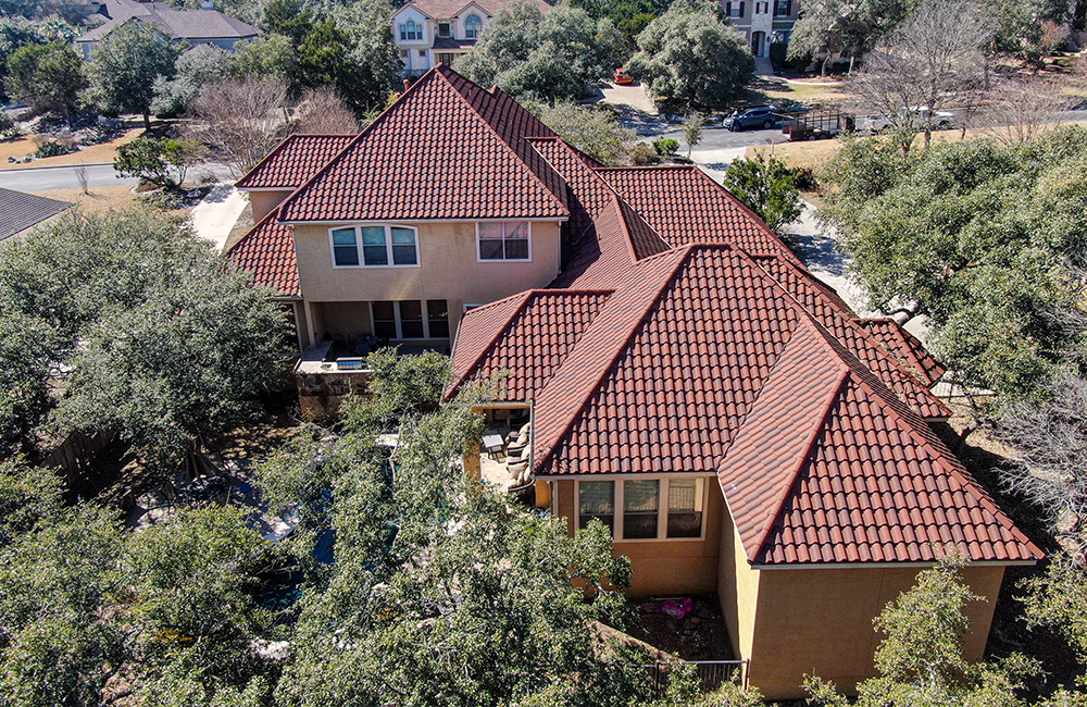 an aerial view of an austin home with red and tan clay tiles on the roof
