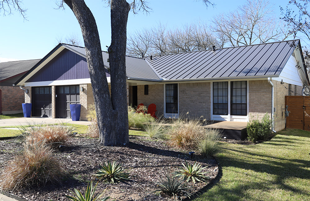 a hip austin home with metal roofing and southern shrubbery